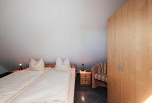 a small bedroom with a bed and a chair at Bernstein-Fewos ca 15 Gehminuten zum Ostseestrand in Zempin