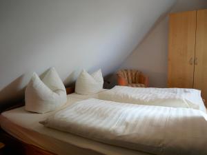 a bed with white sheets and pillows on it at Bernstein-Fewos ca 15 Gehminuten zum Ostseestrand in Zempin