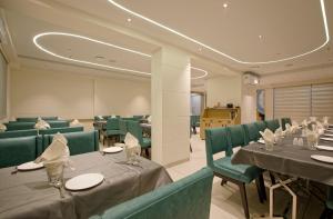 SarkhejHOTEL AURELLIA的有桌子和绿色椅子的餐厅