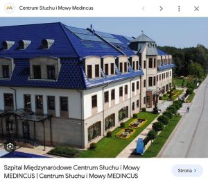 a building with a blue roof on a street at Apartamenty i pokoje gościnne pod lasem in Nadarzyn