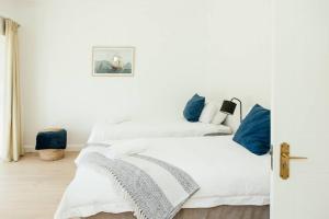 1 dormitorio blanco con 2 camas y almohadas azules en Avisa Villa - 4 bedroom Villa with Majestic Ocean Views en Ciudad del Cabo