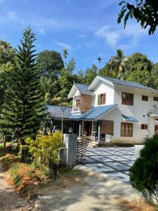 a white house with a tree in front of it at Munnar Village Homes in Munnar