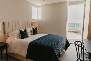 a bedroom with a bed with blue pillows and a window at Clifftops Lodge in Portland