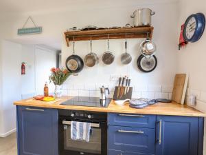 a kitchen with blue cabinets and a counter with pots and pans at Silva in Penmon