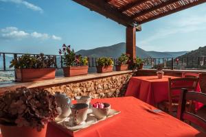 ProssediにあるLocanda Perseiのバルコニーに赤いテーブルクロスと植物を使用したテーブル