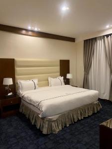 a bedroom with a large bed with white sheets and pillows at Aral Hotel Apartments in Tabuk