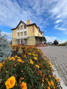 a large yellow building with flowers in front of it at Бобри плюс in Novovolynsʼk