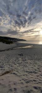 a sandy beach with a cloudy sky and the ocean at 1 Courtyard Mews in Penzance