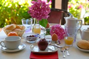 - une table avec des aliments pour le petit-déjeuner et un vase de fleurs roses dans l'établissement Hotel San Filis, à San Felice del Benaco