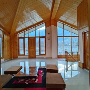 un grand salon avec des fenêtres et une table dans l'établissement Himachal Villa 3 BHK, à Kulu