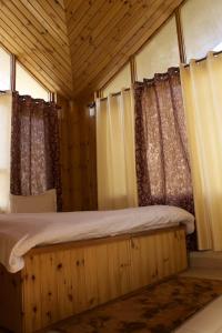 a bedroom with a wooden bed with curtains at Himachal Villa 3 BHK in Kulu