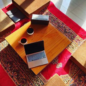 - un ordinateur portable sur une table en bois avec deux tasses de café dans l'établissement Himachal Villa 3 BHK, à Kulu