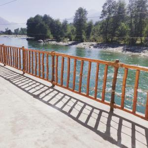 a wooden fence next to a river at Himachal Villa 3 BHK in Kulu