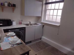 een kleine keuken met een wastafel en een vaatwasser bij 1 Courtyard Mews in Penzance