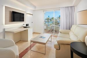 a living room with a couch and a table and a tv at Grupotel Acapulco Playa - Adults Only in Playa de Palma