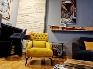 a living room with a yellow chair and a piano at Apartman Kalina in Novi Sad