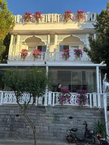 um homem de pé na varanda de uma casa com flores em hi HOTEL IVY BÜYÜKADA em Adalar