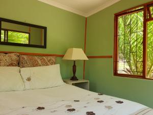 - une chambre avec un lit doté d'une lampe et d'une fenêtre dans l'établissement The Farmhouse Palm Tree Cabin, à Stellenbosch