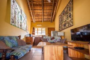 sala de estar con sofá y TV de pantalla plana en African Sunsets (Bophirimo Self-Catering Guest House), en Kasane