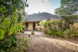 uma casa amarela com um telhado de palha e um quintal em African Sunsets (Bophirimo Self-Catering Guest House) em Kasane