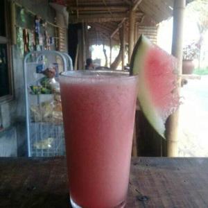 a drink sitting on a table with a slice of watermelon at BaliFarmhouse in Banjarangkan