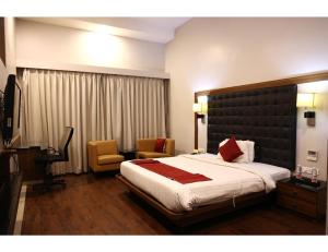 a hotel room with a large bed and a chair at The Fern Residency, Kakinada, Andhra Pradesh in Kākināda