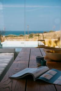 ein offenes Buch auf einem Holztisch mit einer Schüssel Essen in der Unterkunft Luxury Cycladic Villa with Seaview and MiniPool in Naxos Chora