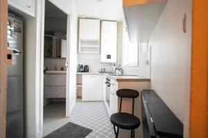 a small kitchen with white cabinets and black stools at Cozy love cocoon in Boulogne-Billancourt's heart in Boulogne-Billancourt
