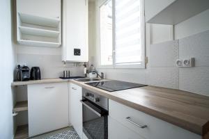 a kitchen with white cabinets and a wooden counter top at Cozy love cocoon in Boulogne-Billancourt's heart in Boulogne-Billancourt
