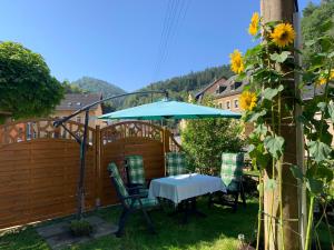 una mesa y sillas bajo una sombrilla en el patio en Ferienwohnung am Bächelweg, en Bad Schandau