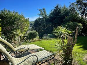 two chairs and a bench in a garden at Domaine des Tuilières avec Jacuzzi in Vallauris