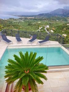 a swimming pool with chairs and a palm tree at Villa ArGia with private pool in Georgioupoli