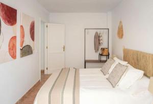 ein weißes Schlafzimmer mit einem Bett und Gemälden an der Wand in der Unterkunft Apartamento Jaira in Playa Honda