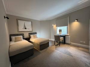 sypialnia z 2 łóżkami, biurkiem i oknem w obiekcie Star London Warwick Mansions 3-Bed Haven w Londynie