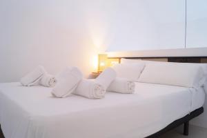 a white bed with white pillows and a lamp at Palacete del Águila in Córdoba