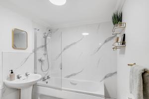 uma casa de banho branca com um chuveiro e um lavatório. em Luxury 2 Bed City Centre with Parking em Norwich