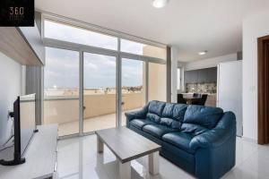 un sofá azul en una sala de estar con una gran ventana en Central & Spacious Penthouse w/ 1BR + City View by 360 Estates, en Msida