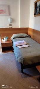łóżko z drewnianym zagłówkiem oraz stół z ręcznikami w obiekcie Hotel Cortina w Rimini