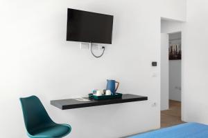 sala de estar con silla azul y TV en la pared en Double D House, en Olbia