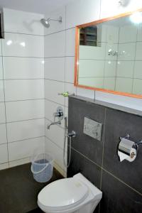 a bathroom with a toilet and a mirror at Omsam Guest Home in Varkala
