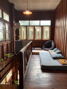 a room with a bed and a couch and windows at Yor Song Hostel Pai in Kampong Huaibū