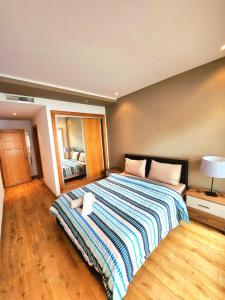 a bedroom with a large bed with a striped blanket at La perle in Nouaceur +13 photos