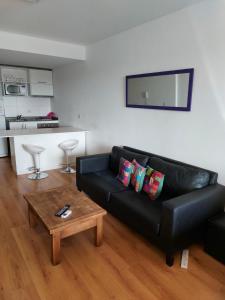 a living room with a black leather couch and a table at Excelente Departamento, piso alto in Buenos Aires