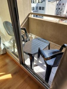una mesa y sillas en un balcón con ventana en Excelente Departamento, piso alto en Buenos Aires