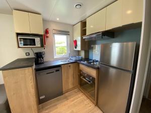 a kitchen with a stainless steel refrigerator and wooden cabinets at 318 Emplacement prestige à Mer et Soleil 5* in Les Sables Vignier