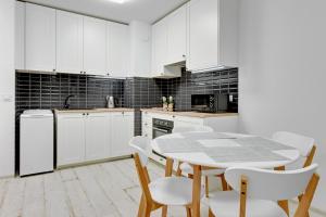 a kitchen with white cabinets and a table and chairs at Flatbook - City Center SPA Apartments Waterlane Island in Gdańsk