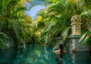 a woman sitting in a pool of water with palm trees at Royal River, Luxury Hotel - Adults Only in Adeje
