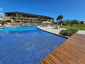 a swimming pool in a resort with tables and chairs at Eco Resort Praia dos Carneiros - Flats & Bangalô - LocarHouse in Tamandaré