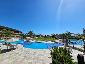 a pool at a resort with chairs and umbrellas at Eco Resort Praia dos Carneiros - Flats & Bangalô - LocarHouse in Tamandaré