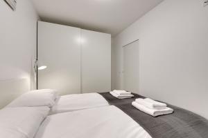 a white bedroom with a large bed with towels on it at Flatbook - City Center SPA Apartments Waterlane Island in Gdańsk